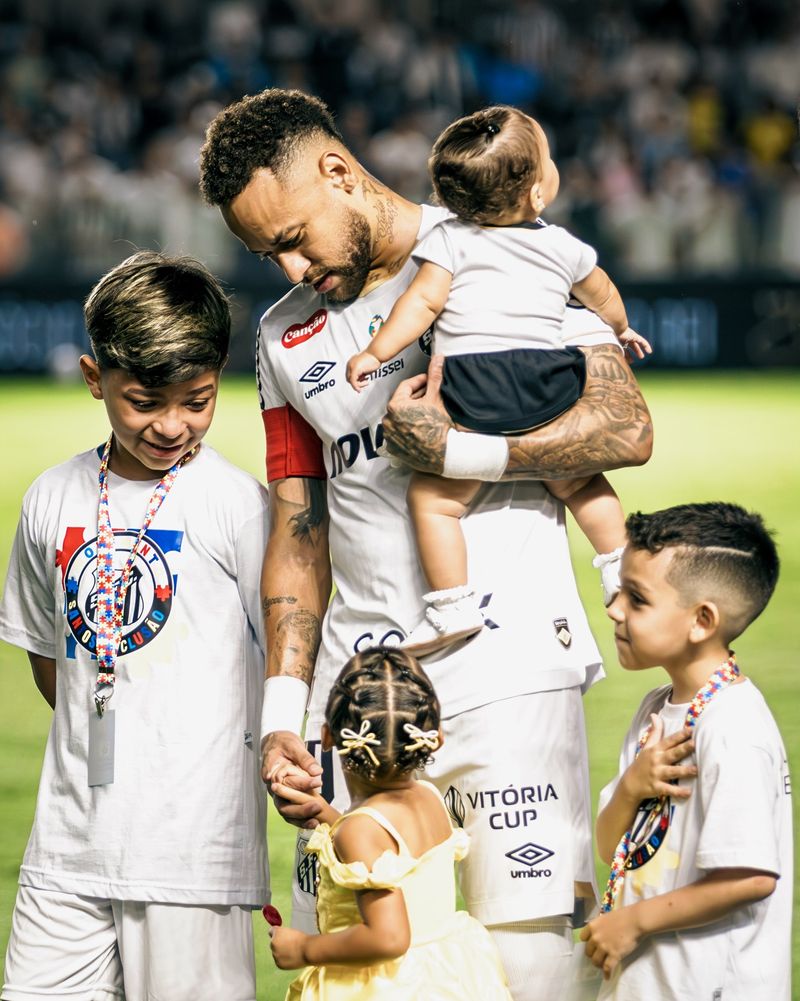Jogador entrando em campo acompanhado de crianças