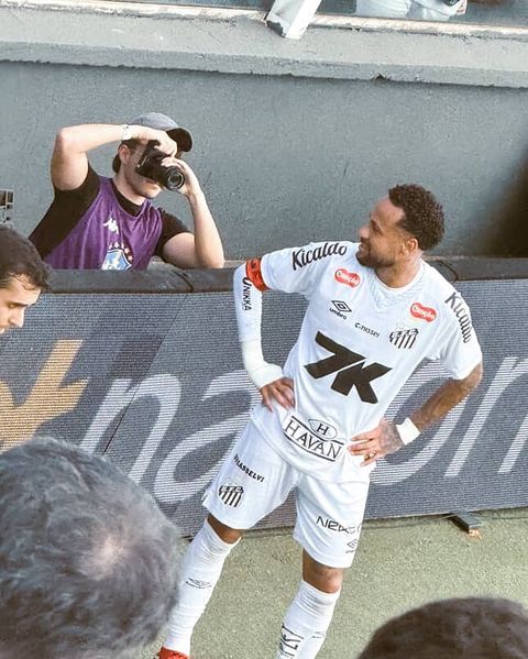 João Jardim fotografando à beira do campo durante partida de futebol profissional